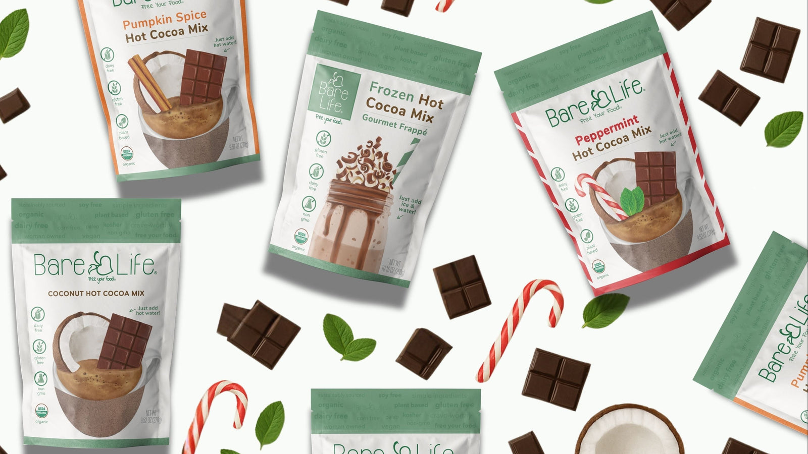 Bare Life hot cocoa mix packages with chocolate pieces and candy canes on a white background