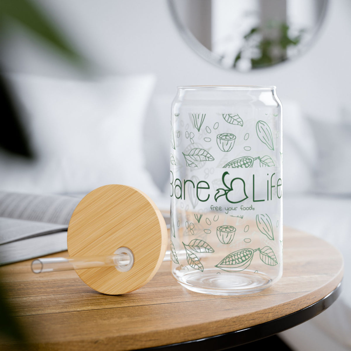 Bare Life Eco-Chic glass tumbler on a wooden table with its bamboo lid and clear straw resting beside it