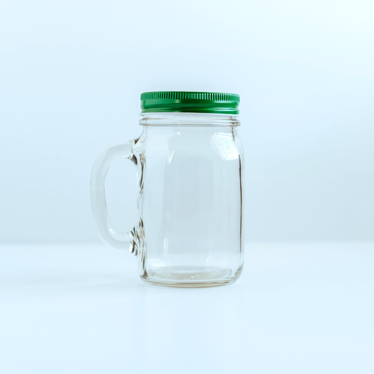Clear Bare Life glass mason jar with handle and green screw-top lid attached