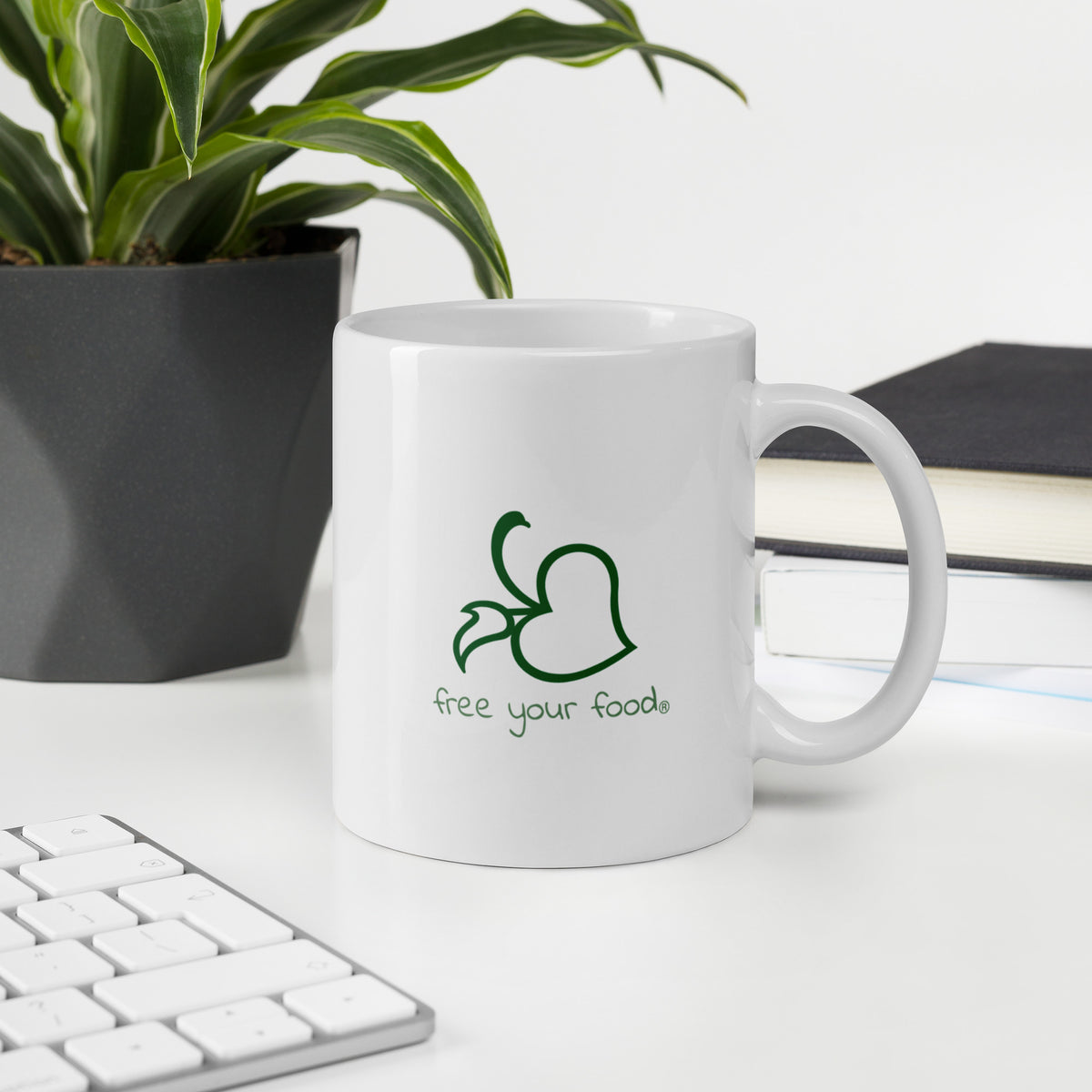 Logo side of the Bare Life Keep Calm and Cocoa On mug on a desk beside books, a plant, and a keyboard